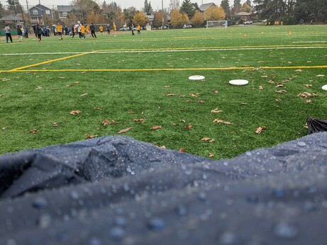 pov from under a rain poncho looking out over an ultimate frisbee game