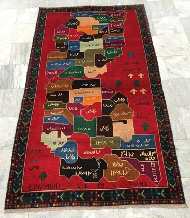 Photograph of a rectangular, red rug with what look like two rectilinear maps each with dozens of labelled districts, plus marginal annotations and arrows.
