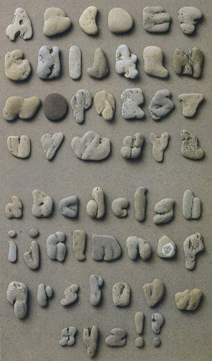 A typeface set that consists of uppercase then lowercase letters, followed by an exclamation mark and question mark, placed on a light-grey surface. Each one is a pebble resembling the letter or mark in question. Some of the resemblances are impressive, and the overall effect is marvellous. The pebbles are mostly shades of grey, many tinged yellow or brown, and their textures give them great variety of character and appearance.