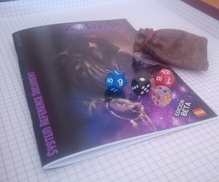 Foto de un ejemplar físico de la BETA preliminar de "Zodiac 2.5: System Reference Document". Se ve la cubierta (con la maravillosa ilustración de "The Warlock" realizada por Daniel Jimbert) junto a la bolsita de lino y los 4 dados que he regalado a cada beta-tester junto a su librillo: 1d12 azul perlado, 1d12 rojo perlado, 1d6 de apuestas japonés negro con puntos blancos y 1d6 de apuestas transparente con puntos rojos, azules o amarillos dependiendo de cada cara.