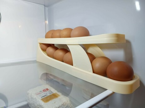 A plastic contraption inside a refrigerator. It forms two levels where eggs can sit on a slight slope. The fresh eggs are inserted at the top front and roll down and around a curved drop at the end, then forward again at the lower end, where the oldest egg can be easily retrieved at the front bottom. A first-in-first-out buffer.
