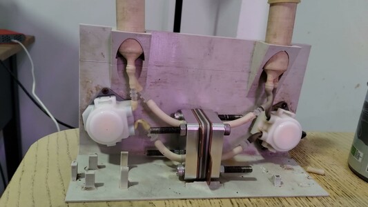 Flow battery test cell with peristaltic pumps. Aluminum cell around white tubing and hardware