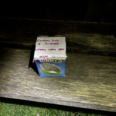 A mint Terry’s chocolate orange on a bench with a note saying “Random act of kindness. Happy new year. Enjoy. 🙂”
