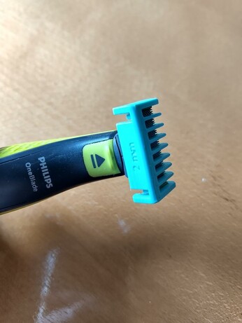 Teal colored comb on a Philips One Blade device.