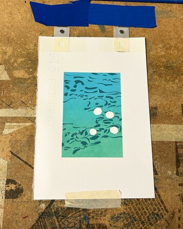 A screenpring in progress showing a gradient of cyan to turquoise with darker blue shapes printed over.