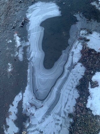A large icy puddle with increasingly dark bands as you move towards the middle