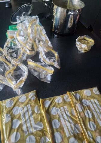 Snert wordt op een zwart keukenblok uit de pan in zakjes gedaan voor de diepvries. 3 zakjes zijn al gevuld rn er liggen nog een boel klaar.