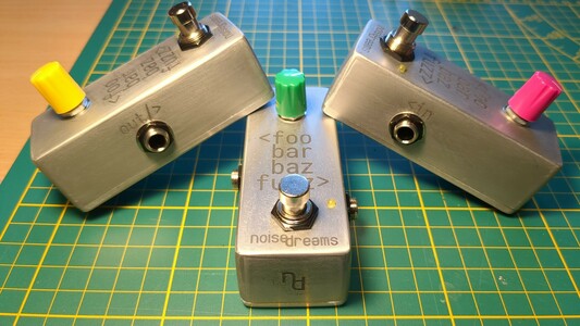Three copies of the foobarbaz fuzz guitar pedal, views from different sides
