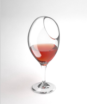 A glass of red wine where the hole is designed at the top but on the side which makes it impossible to drink from.