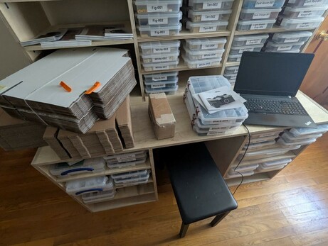 A very messy desk top with, among other things, a small cardboard box. The box is about 4 x 4 x 8 inches and completely unremarkable. The box is filled with lead pellets and weighs 25 pounds.