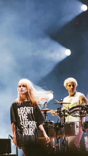Hayley Williams on stage with Zac Farro. She is wearing a long black shirt that reads "abort the supreme court"
