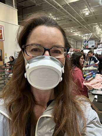 Middle aged women with glasses in a crowded Costco wearing a Flomask KN95 mask.