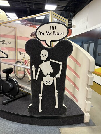 Picture of a foam skeleton on a black felt background, posed with his hand on his hip and a small wave. Above him is a word balloon that says “Hi, I’m Mr. Bones”