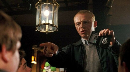 In a pub, an off-duty British police officer holds up his badge and pointing at someone as he demands to know their date of birth