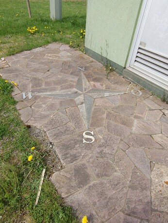 Windrosenmosaik, das in einen Plattenweg eingelassen ist.