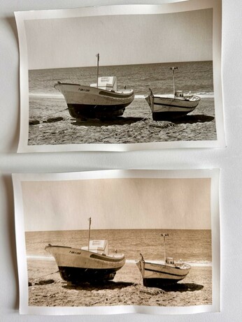 A black and white darkroom print of two boats on a sandy beach. There are two versions of the same print; a normal print and a lith print. The with print has yellow/brown tones.