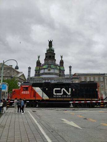 Foto. Strassenszene mit schwarzer Diesel-Lokomotive.