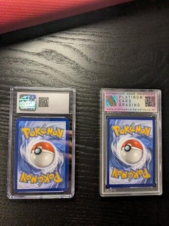 The picture shows two graded Pokémon cards encased in protective slabs from behind.