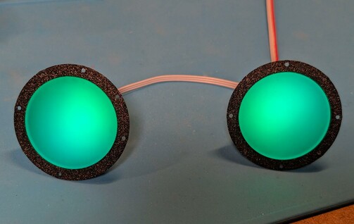 Two green glowing circles with black border. They're spaced about eye-distance apart. The black border has holes in it.