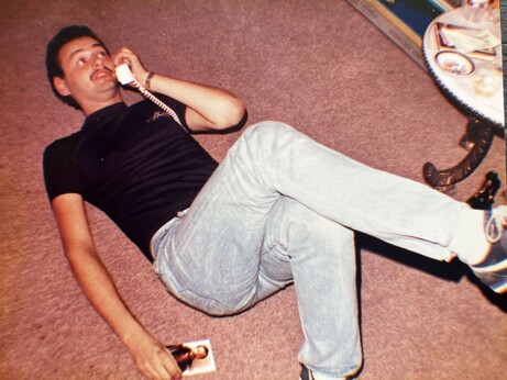 It’s 1980s New York and a young man with a very small mustaches laying on the floor on the phone chatting to someone. Though he’s white he is sporting a tan. The young man is wearing a T-shirt from London’s heaven club. Everything about the picture speaks 80s clone. Also pictured is part of a table with an ashtray. The young man who appears to be in his 20s is holding the picture of another man in his right hand.

And, yes gentle reader, that young man was me.