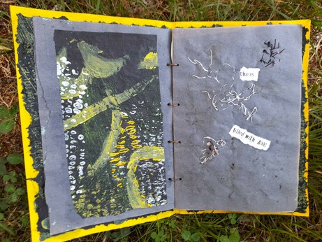 #3: double page. left: maize print in white and some yellow with yellow abstract lines painted on black tissue paper. Some yellow enhancements with intuitive embroidery. Right: white intuitive stitching with thin paper yarn and the printed words 'chaos' and 'filled' with AWE. The challenge: wild embroidery appears on the reverse and serves as inspiration for new combinations.