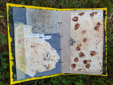 #5 double page. Left: abstract collage of used coffee filter with holes and intuitive stitching with fine black and white paper thread and some parts of a used tea bag. One with printed floral pattern. The printed words 'filled with scents'.
Right: a big rectangle of a used coffee filter with hammer printing of rose petals. Intuitive stitching in red and grey, fixed on grey krafft paper.