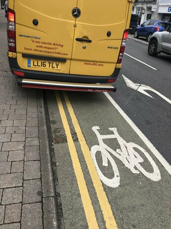 Van parked in bike lane with message printed on rear reading "Is our courier driving with respect?"