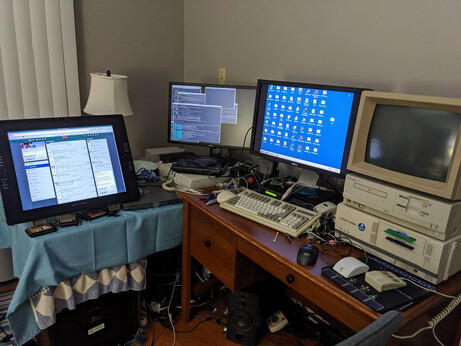 A very crowded desk containing a 4:3 wacom graphics tablet, two other LCD's, one of which is showing a windows 98 desktop running on a gateway desktop PC and the other two showing FVWM on my newest computer. There's two more old beige box computers on my desk; an Epson PC-486GR and an NEC PC-9821Ce2. I'm using old keyboards from the late 80's and early 90's, and three button mouses. There's also a Roland MT-32 synthesizer and a Sound Canvas SC-55K just barely visible. And a sega mega drive and various cartridges.