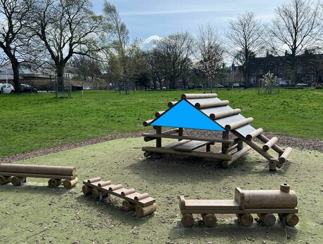 Photograph of a wooden climbing frame in a park, with a wooden play train in front of it. The climbing frame has a triangle superimposed on it to show an obtuse angle.