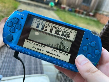 A photo of my blue PSP showing the GameBoy version of Tetris running on the screen.