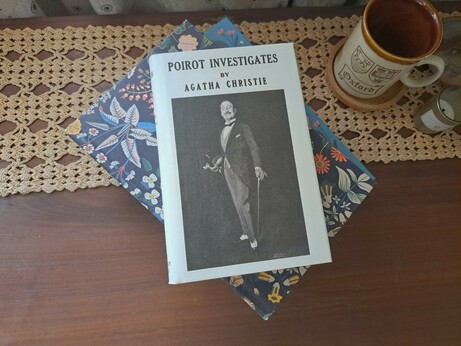 The Poirot book mentioned with a black and white cover over some other books