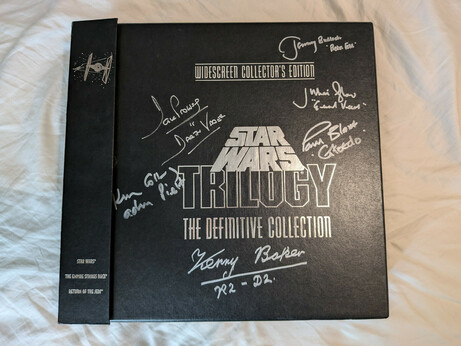A picture of a huge laserdisc box set of the Star Wars Trilogy - the Definitive Edition. Many actors from the trilogy have signed it, including David Prowse (Darth Vader), Kenny Baker (R2D2), Jeremy Bulloch (Boba Fett), Paul Blake, (Greedo), Julian Glover (General Veers), and Kenneth Colley (Admiral Piett)