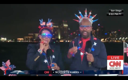 an image of 2 whackos dressed in some weird Murican-themed lighting. There is a coastline and buildings seen in the background.
Oh and yeah, they are CNN anchors!