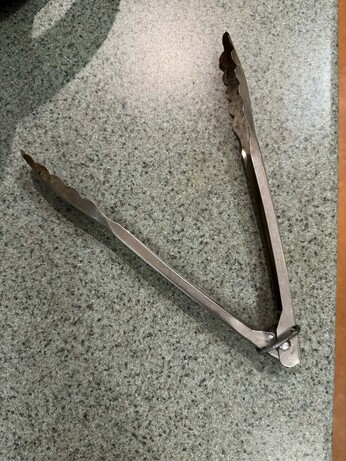 A pair of pressed metal food tongs in the open position (as they’ve been for over 20 years)