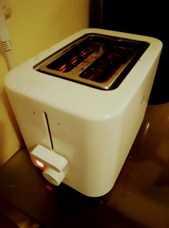 Toaster filaments glow as toast toasts in the toaster, round side down.
