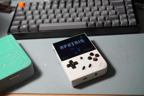 a white emulator machine in the formfactor of a gameboy. On the screen is "apotris", a version of tetris.