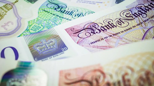Close up of details on a handful of banknotes on top of each other, showing the "Bank of England" name and other details in bright colours