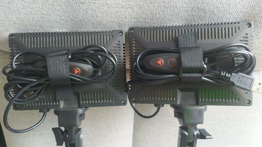 A pair of cheap USB lights for helping light photography. The have a rectangular light box on each one and on the back the cable is tied down with a strap going through a 3D printed block glued to the device.
