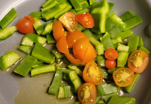 Cactus chopped up in a pan with cherry tomatoes, in olive oil, bright green and red tomatoes