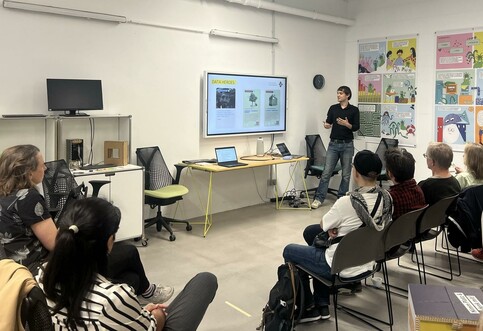 GI-Referent Nico Dankel stellt das Spiel Data Heroes in einem Workshop-Raum vor, Menschen auf Stühlen hören ihm zu.