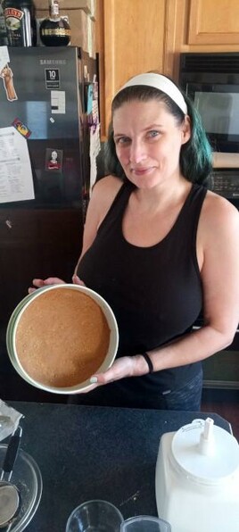 My SO is standing in our kitchen, holding a baking pan with a Graham cracker crust in the bottom.