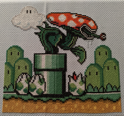 A cross stitched image of a piranha plant from Mario with the head of a xenomorph from Alien. The plant is coming out of a pipe and at the base of the pipe are yoshi eggs with split tops like a facehugger egg.