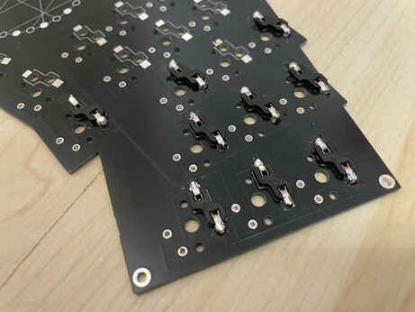 Photo of a mechanical keyboard PCB in black with 9 kailh hotswap switch sockets soldered on