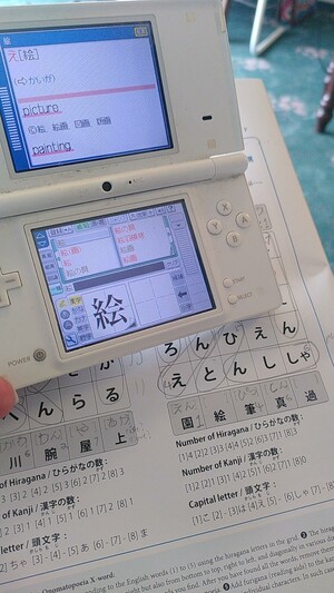 A nintendo ds showing the defenition for 絵　(picture) over a wordsearch.