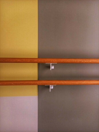 Abstract pattern consisting of three colored panels in yellow, grey and white are crossed by two slim bars of brown color held in place by two white metal holders,  together forming an arrangement reminiscent of the works of Piet Mondrian