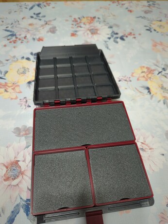 A Gridfinity box, whose outer shell is printed from a dark grey plastic. The inside boxes are a dark red plastic, with dark grey flip lids to match the outer shell. Two boxes are 2 by 2, and one is 4 by 2. All the flip lids are closed. The latch is visible, and it is the same dark red as in the inside boxes.