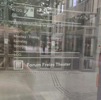 Glasscheibe am Eingang zur Stadtbibliothek Düsseldorf mit den Öffnungszeiten