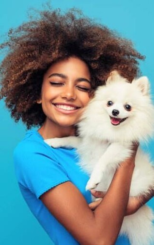 A lovely young woman hugging her little white dog