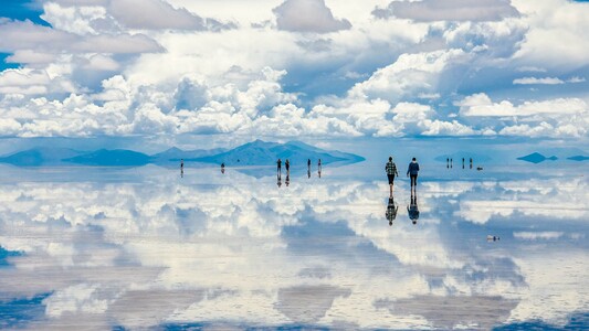 People walking through an endless sky of blue with white fluffy clouds