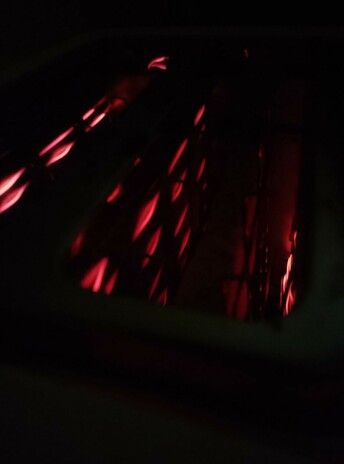Filaments glow as toast toasts in the toaster, round side down.